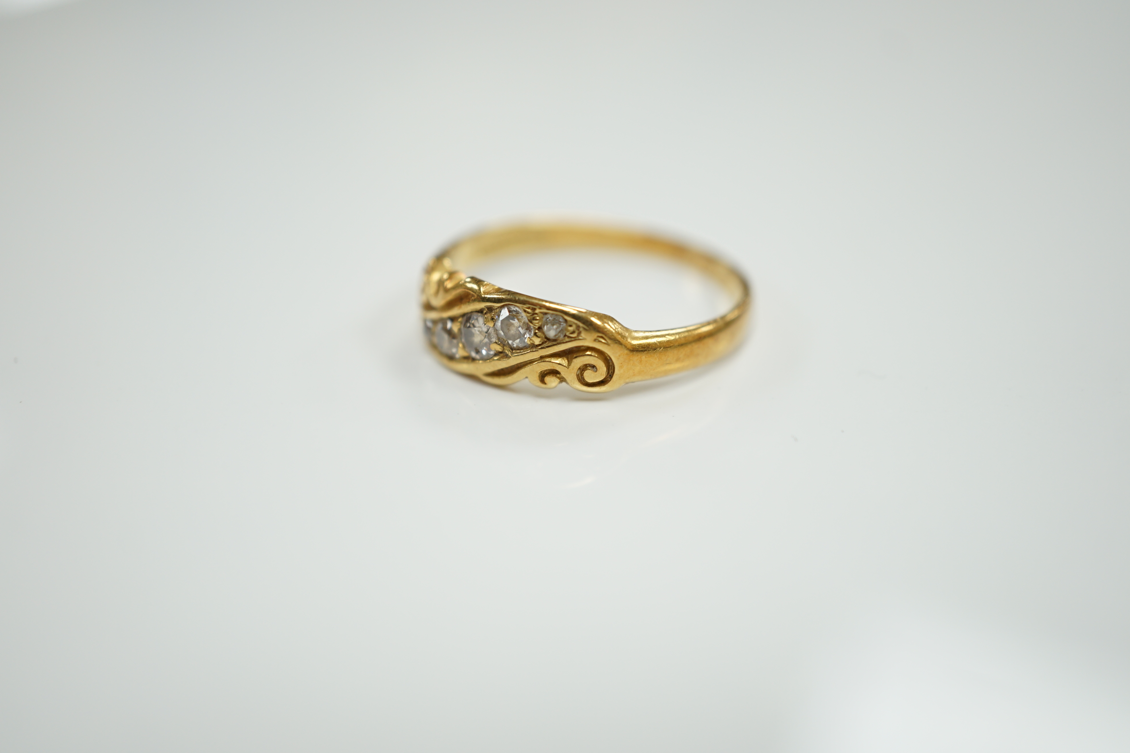 An early 20th century 18ct and graduated five stone set diamond ring, with scrolling setting, size Q, gross weight 3.4 grams.